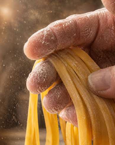 Préparation traditionnelle de pâtes italiennes — Zoom : Main de maître artisan & fettuccine fraîche