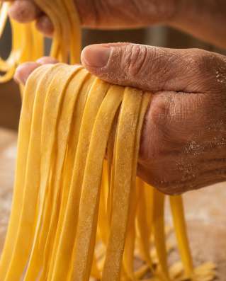 Préparation traditionnelle de pâtes italiennes — Zoom : Main farinée & texture du pâton découpé